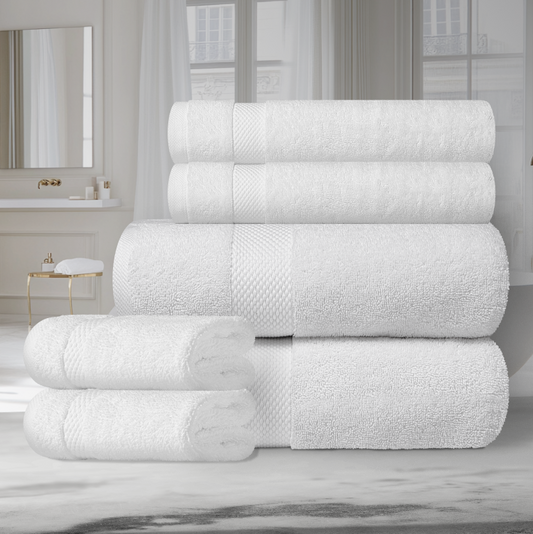 Stack of folded white Turkish cotton towels placed on a surface with a mirror and window in the background.